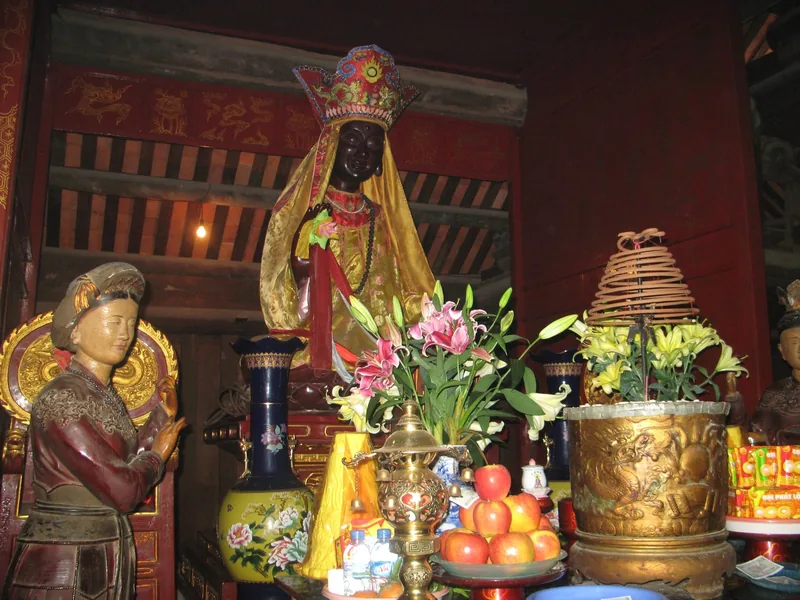 Tượng thần đội mũ miện cùng các tượng hầu và lễ vật hoa quả bên trong chùa Dâu ở Bắc Ninh.